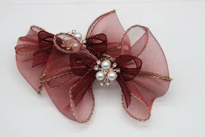 Dettaglio di fiocchi in organza rossa con bordi dorati e centro in perle e strass