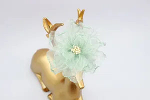Dettaglio di fiore in organza verde menta con stami bianchi su decoro dorato a cervo