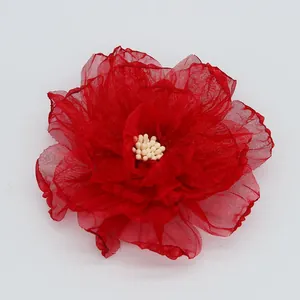 Détail de la pince à cheveux fleur rouge avec pétales et centre perlé blanc