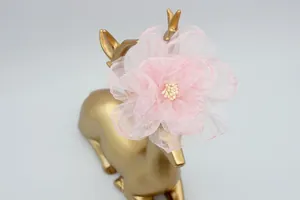 Dettaglio di un fiore in organza rosa con petali a strati e stami di perle su supporto