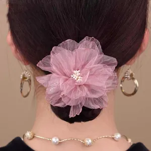 Detailweergave van de roze organza bloem haarclip met parel op het achterkapsel
