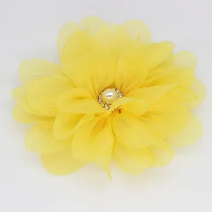 Macro detail of yellow chiffon flower accessory with center pearl and rhinestones