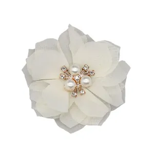 Detailed close-up of ivory chiffon flower with center pearl and rhinestone accents