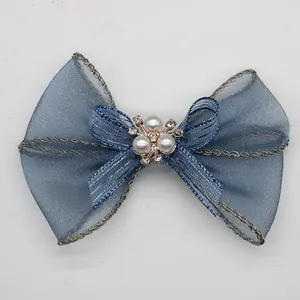 Elegante fiocco in organza blu con perle e strass su una superficie grigia pulita