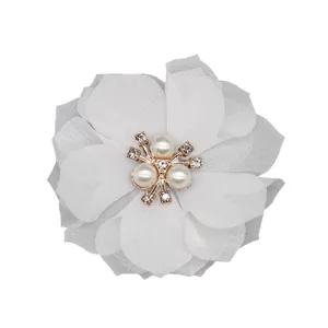 Detail of white chiffon fabric flower with pearl and rhinestone center on rose gold base