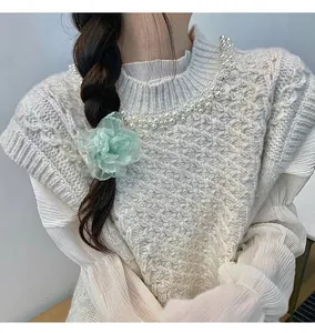 Détail d'une pince à cheveux fleur en organza vert clair sur modèle avec gilet en perles