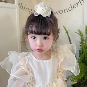 Détail d'une délicate pince à cheveux fleur en organza crème sur une jeune fille en robe
