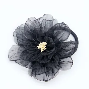 Detail van een zwarte organza bloem haarelastiekje met witte meeldraden en band