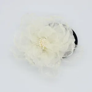 Macro detail van zijden camelia haarstrik met crème bloemblaadjes en parel midden