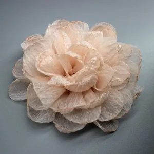 Close-up of light pink organza flower brooch with multilayered 3D petal details
