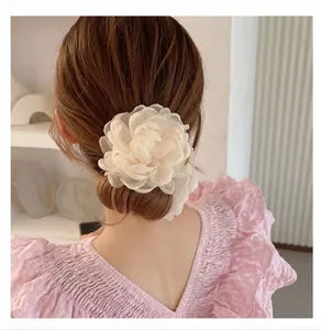 Detail of a large off-white organza peony flower hair clip on a brunette bun hairstyle