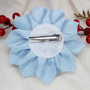 Detail view of the silver alligator clip on the back of a light blue floral hair clip