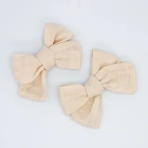 Set of two beige linen bow hair accessories with natural woven texture on white background