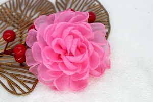 Detail of pink organza fabric flower with layered petals on a soft textured background