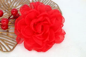 Detail view of handmade multi-layered red organza peony hair clip with soft petals