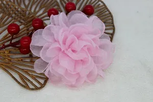 Close-up of pink layered organza flower hair clip on soft white plush background