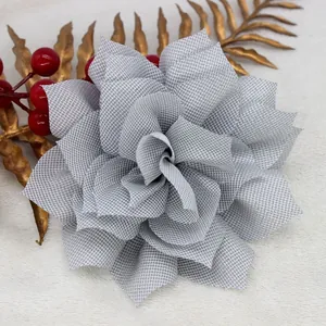 Vista macro de un broche de flor de tela plateada con textura de malla y hilo metálico brillante