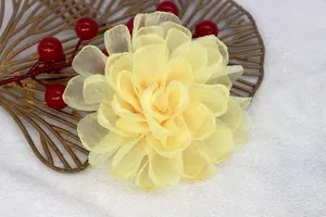 Detail of yellow organza flower on gold leaf tray with fuzzy white background texture