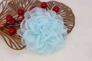 Detailed close-up of light blue organza flower brooch on a decorative gold tray