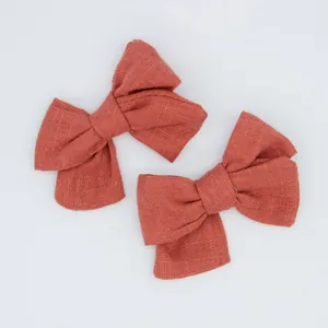 Close-up of two terracotta cotton-linen bows featuring a textured woven fabric finish