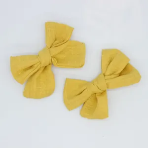 Close-up of bright yellow cotton linen handmade bow hair clips with natural fiber texture
