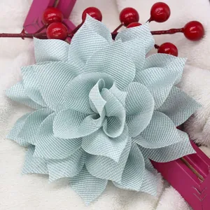 Broche de flor de malla verde claro con purpurina plateada sobre fondo de piel blanca