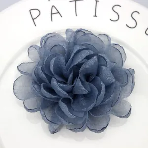 Detail of blue organza flower hair clip with layered petals on white ceramic plate