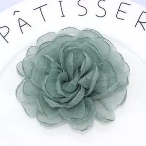 Macro detail of teal organza layered petals with intricate embroidered edge texture
