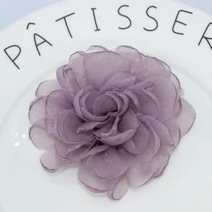 Detailed macro view of a handmade purple organza peony hair clip on a white ceramic plate