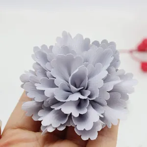 Detail of a 7cm handmade pleated satin fabric flower held in hand for scale and texture