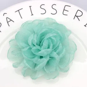 Macro detail of mint green organza fabric flower clip with layered petal texture