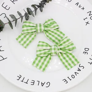 Zweiteiliges Set grüne Gingham-Haarschleifen auf einem weißen dekorativen Porzellanteller
