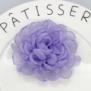 Macro shot of purple layered organza flower hair clip on a white ceramic plate