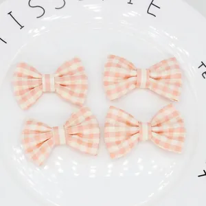 Dettaglio di quattro fiocchi in tessuto a quadretti rosa e bianchi per accessori capelli