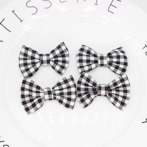 Set di quattro fiocchi in tessuto vichy bianco e nero esposti su un vassoio decorativo bianco