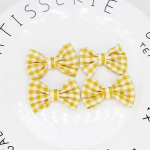 Dettaglio di quattro fiocchi in tessuto vichy giallo su un piatto di ceramica bianca