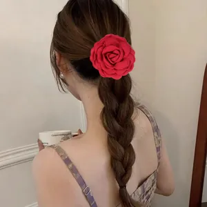 Vue détaillée d'une pince à cheveux rose rouge en tissu sur une coiffure tressée brune