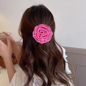 Détail d'une pince à cheveux rose en forme de rose en tissu sur des cheveux ondulés