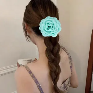 Détail d'une pince à cheveux rose en tissu vert menthe sur une coiffure tressée