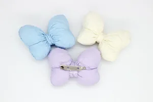 Detailweergave van gevoerde stoffen strikbroches in pastelkleuren met metalen speld