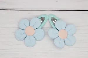 Detailed view of light blue padded flower hair clips with green ribbon wrapped BB clips