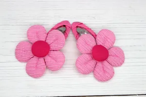 Detail showing the fine rib texture and pink fabric of two sunflower hair clips for girls