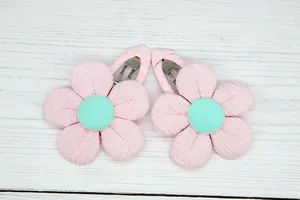 Detail of pink corduroy sunflower hair clips with green center on a light wood background