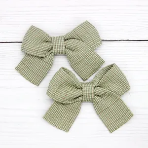 Macro shot of two woven bow hair clips with green and beige checkered patterns