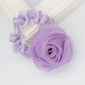 Macro detail of elegant purple fabric rose hair tie showing layered organza petals