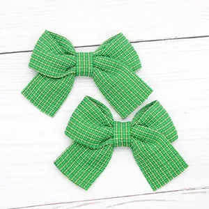 Close-up of a pair of green and white checkered bow hair clips for kids on a white surface