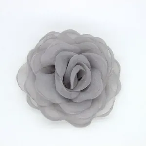 Detalle macro de un elegante broche de camelia en organza gris con pétalos en capas