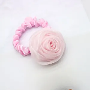 Detail of soft pink chiffon rose hair tie with elegant silk texture on marble surface