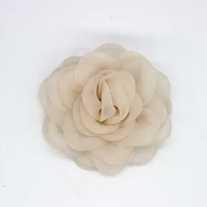 Detalle de una flor de camelia de tela beige con pétalos de organza en capas