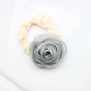 Close-up of elegant cream satin hair scrunchie with a large 3D silver-grey fabric rose decoration